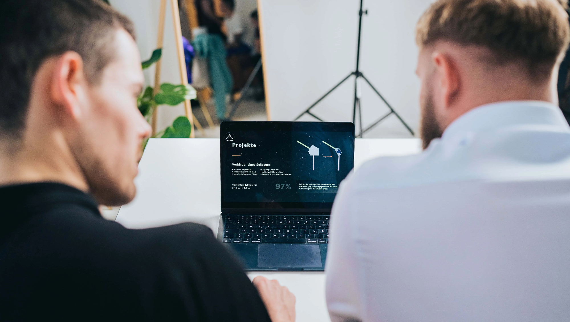 Zwei Ingenieure bewerten eine optimierte Baugruppe am Laptop.